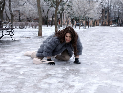 Woman fallen on icy pavement in park