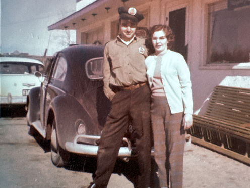 Two people posing beside vintage tow truck outside building
