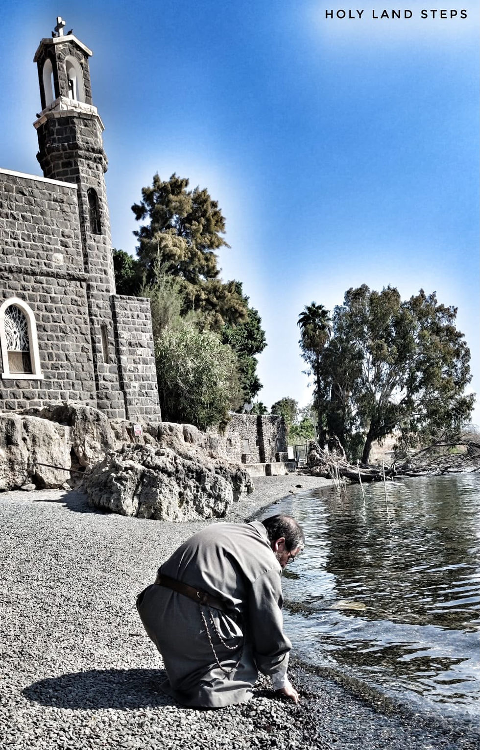 A priest touching the holy waters of the Sea of Galilee.