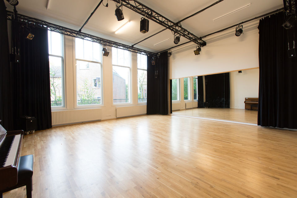 Rustige studio met zwevende houten vloer voor een muziekrepetitie, cursus of training.
Naast de Theaterzaal op de begane grond vind je de Kleine Studio. De ruimte heeft – net als de grotere studio’s - een af te dekken spiegelwand, airconditioning en simpel te bedienen licht- en geluidstechniek. Aangrenzend aan de studio vind je een klein privé tuintje waar je gebruik van kunt maken. De studio is geluiddicht, is te verduisteren en in te richten zoals het jou past. Ook wordt de studio vaak gebruikt als uitbreiding van de foyer, bijvoorbeeld bij een drukbezochte voorstelling, trainingsweekend of symposium.
