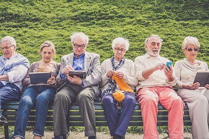 A group of older adults sitting on a chair while using their smart phones