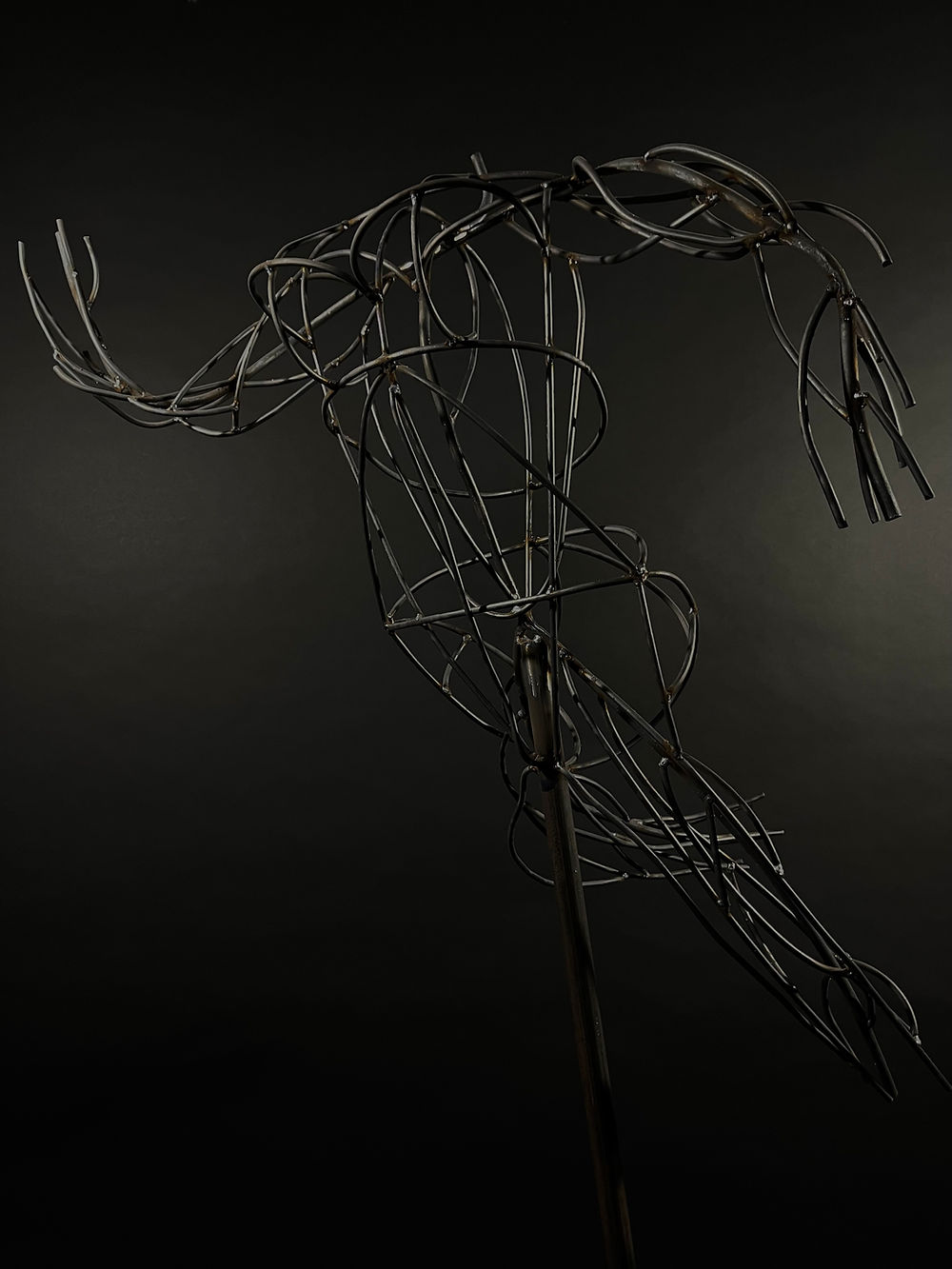 Lineare Skulptur aus gebogenen Stahlstäben, die die Form eines menschlichen Körpers als offene Struktur darstellt