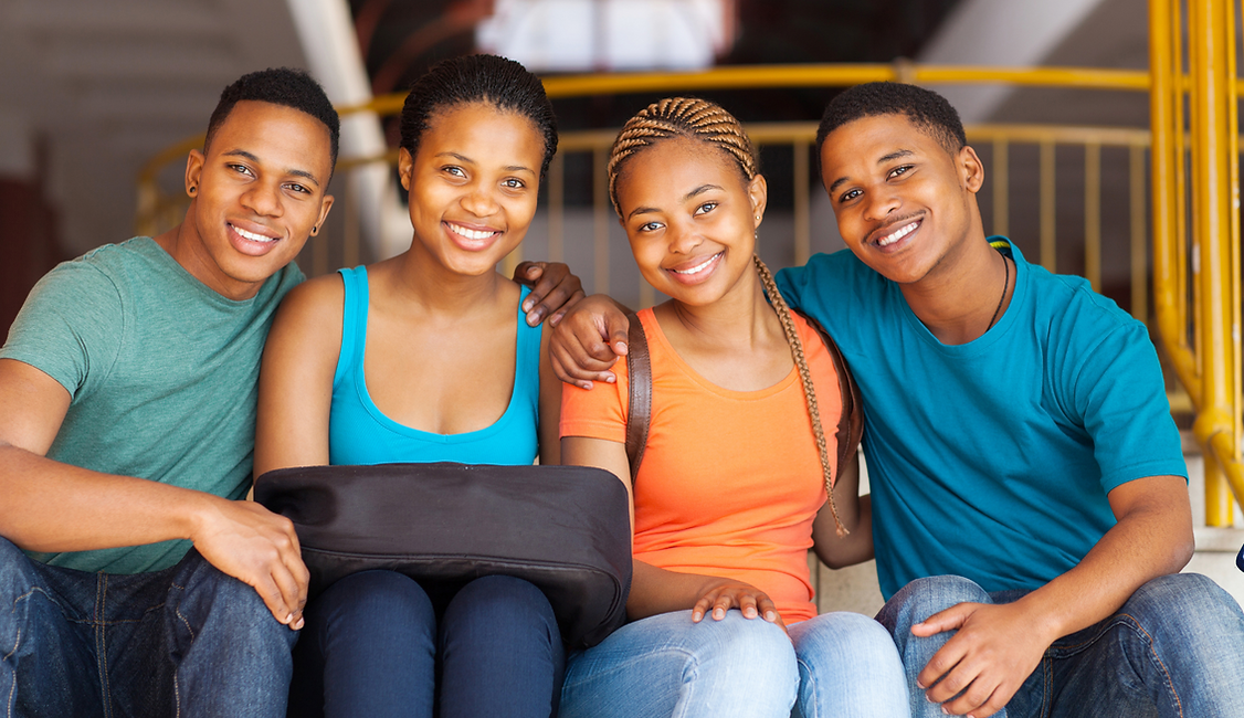 Image of 4 young students of African  decent sitting together smiling 