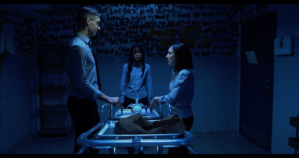 Still from "Escape: A Ghost Story" Showing three people standing around a gurney with a beaker on it