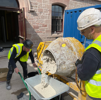 Big mixing machine and a wheelbarrow being filled