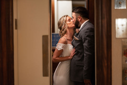 A newly married couple take a moment for a private kiss just before the elevator door closes
