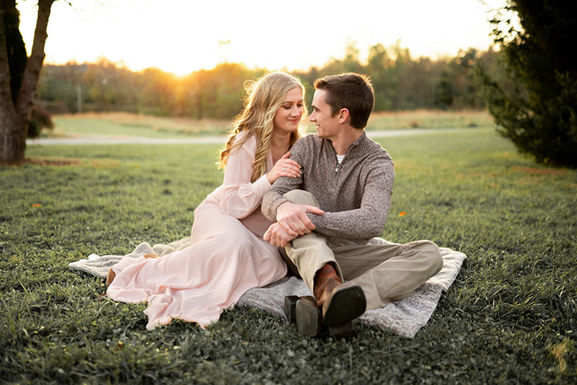 Couple sitting together on blanket during golden hour outdoor session