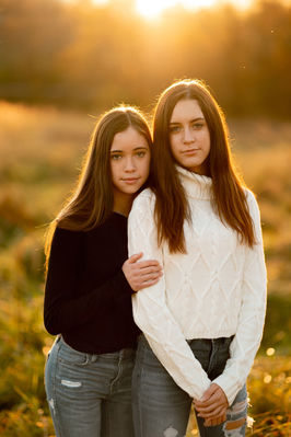 two girls standing together in warm golden sunlight outdoor portrait