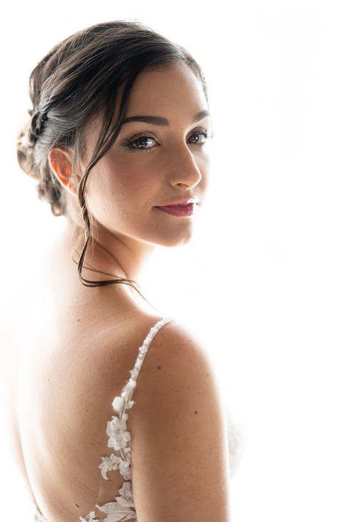 A beautiful dark-haired bride looks over her shoulder with a soft smile on her wedding day in Louisville, Kentucky