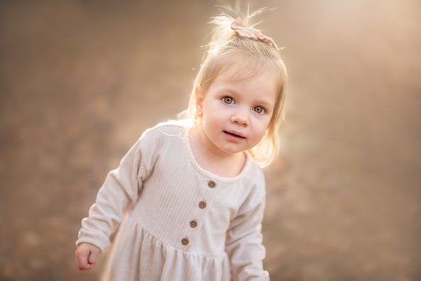 young girl in neutral outfit standing outdoors soft light child portrait