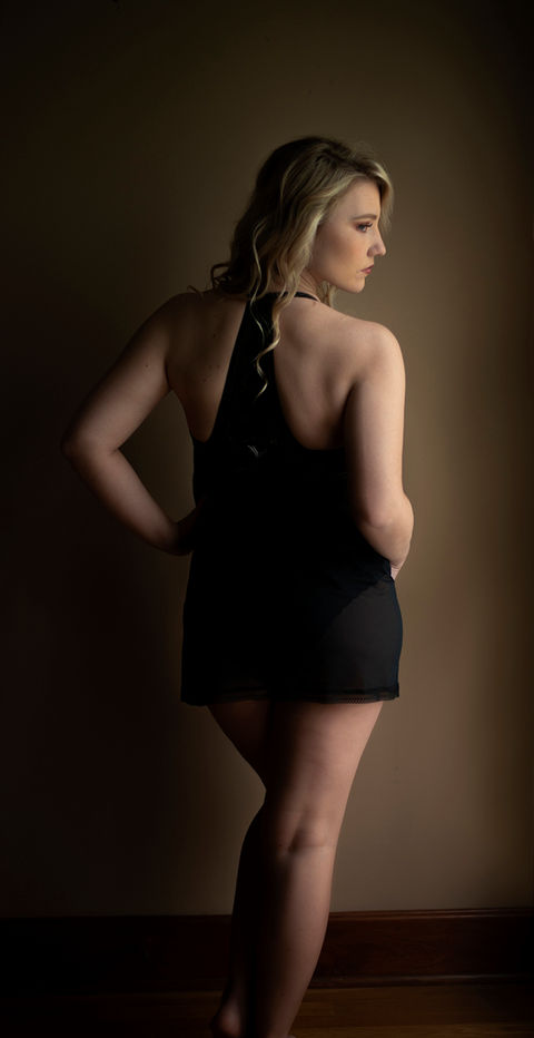 Woman in a black dress walking through soft shadows, creating a moody and elegant boudoir-inspired silhouette.