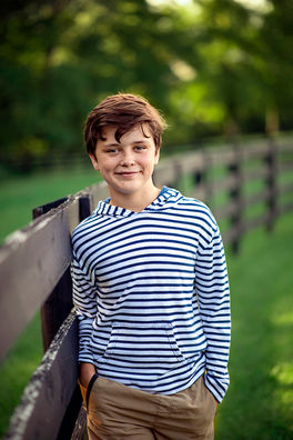 young boy portrait outdoors leaning on wooden fence in soft natural light Louisville family photographer