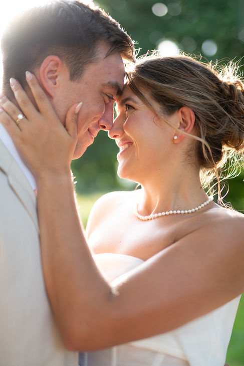 Close-up golden hour portrait of a smiling bride and groom embracing outdoors during a romantic Louisville wedding.