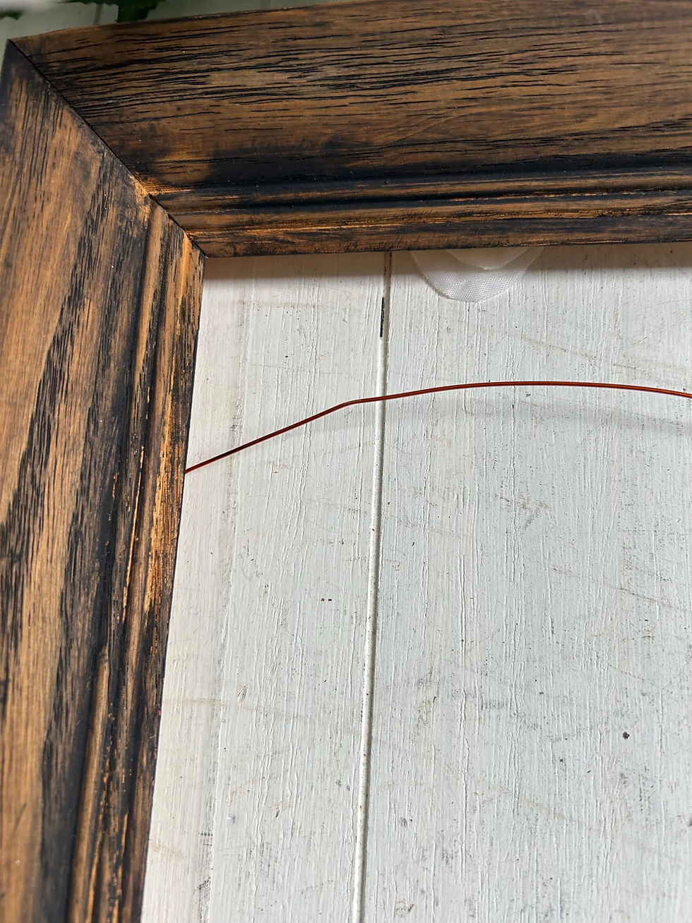Corner of a wood blackwashed vintage picture frame with wire.