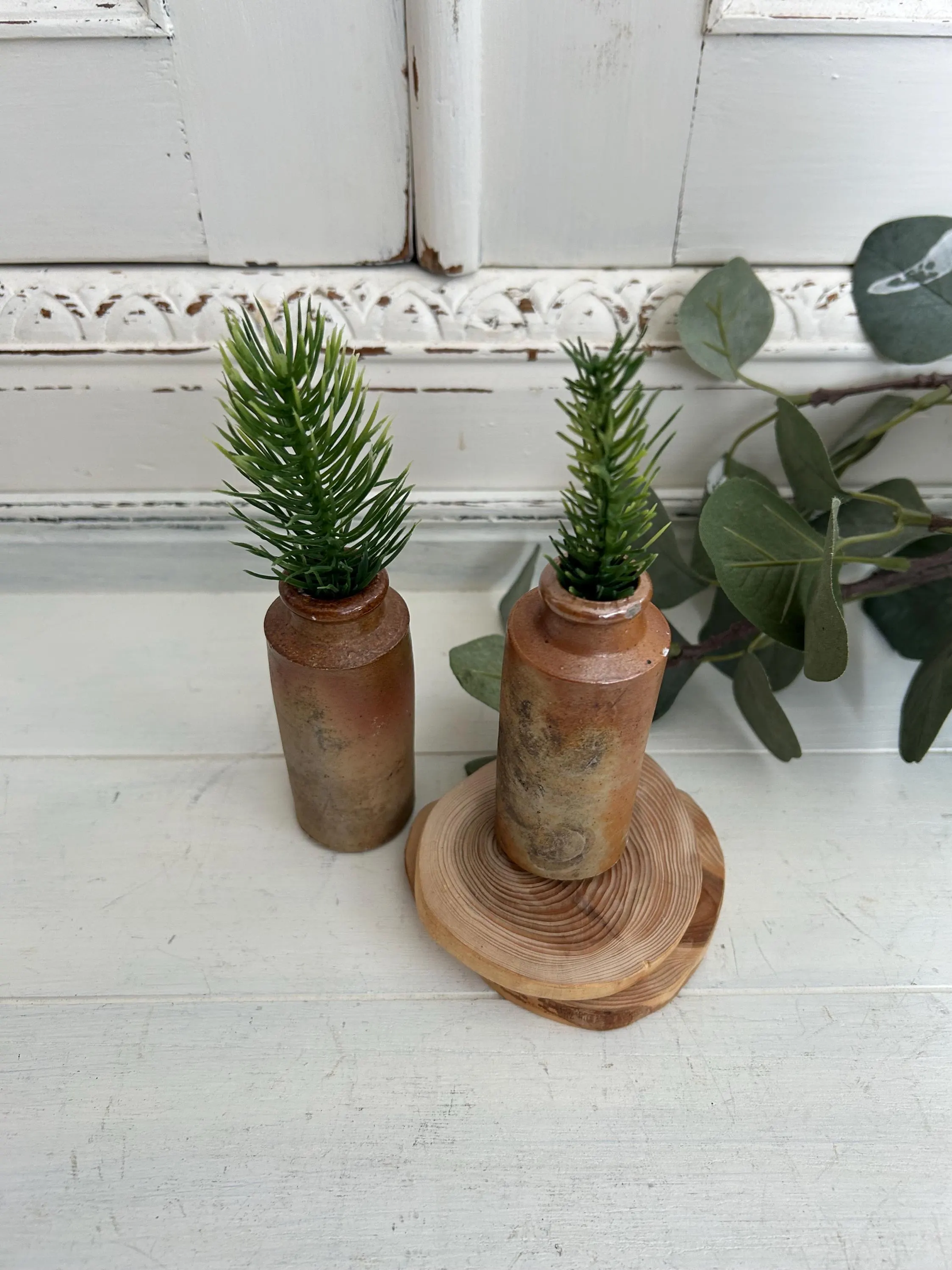 Two antique ceramic inkwells, one on wood slice