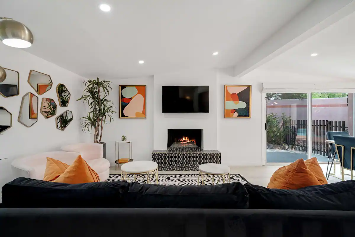 living room in palm desert vacation rental with black velvet couch, modern decor, and glass sliding door to backyard with private pool