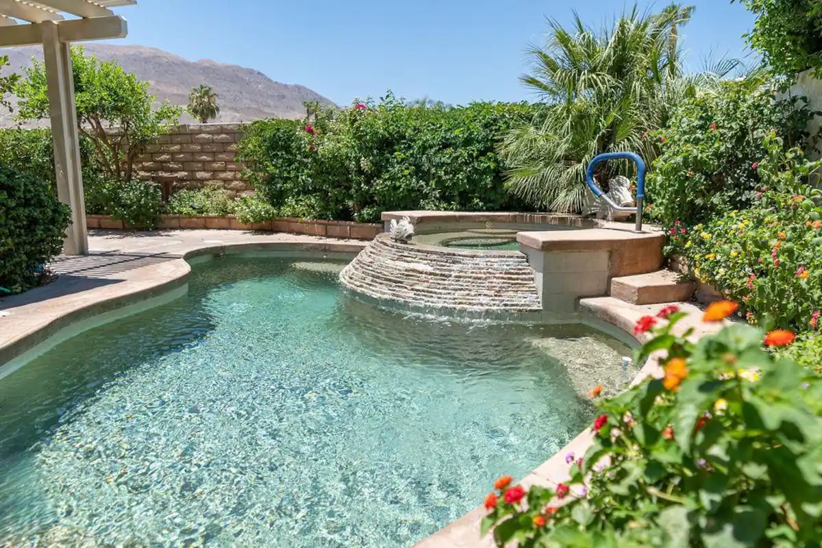 Private pool at Rancho Mirage vacation rental home with jacuzzi waterfall into the pool and surrounded by desert greenery