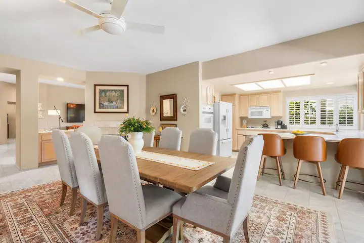 dining room in Rancho Mirage vacation rental with 8-seater dining table, ceiling fan, and open concept kitchen