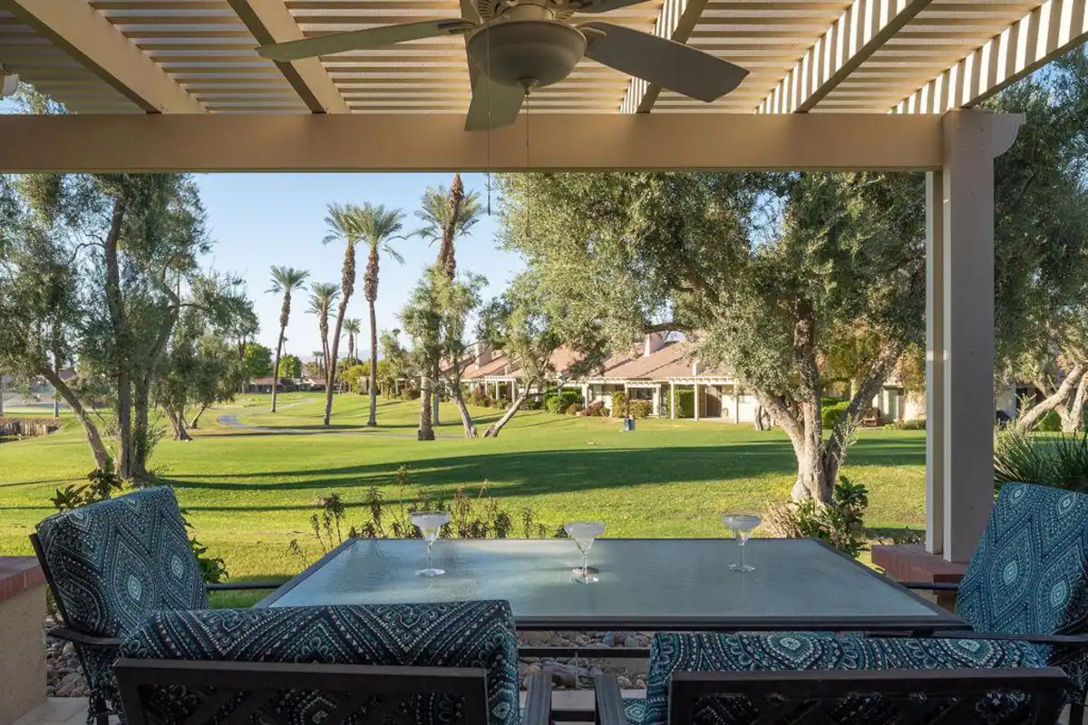 an outdoor seating area at a Coachella valley vacation rental with patio table, pergola, and ceiling fan