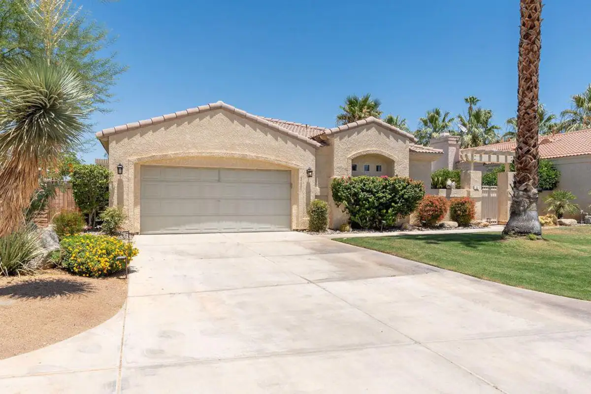 street view of Rancho Mirage vacation rental with two-car garage, green lawn, and large palm trees