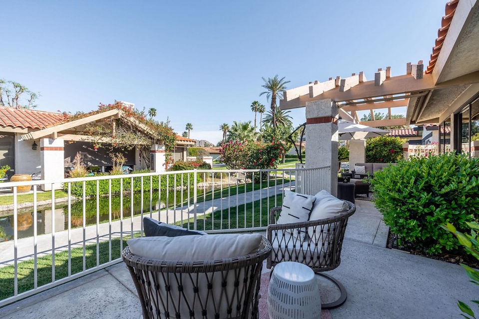 outdoor sitting area at Coachella Valley rental with padded wicker swivel chairs and a view of the creek.