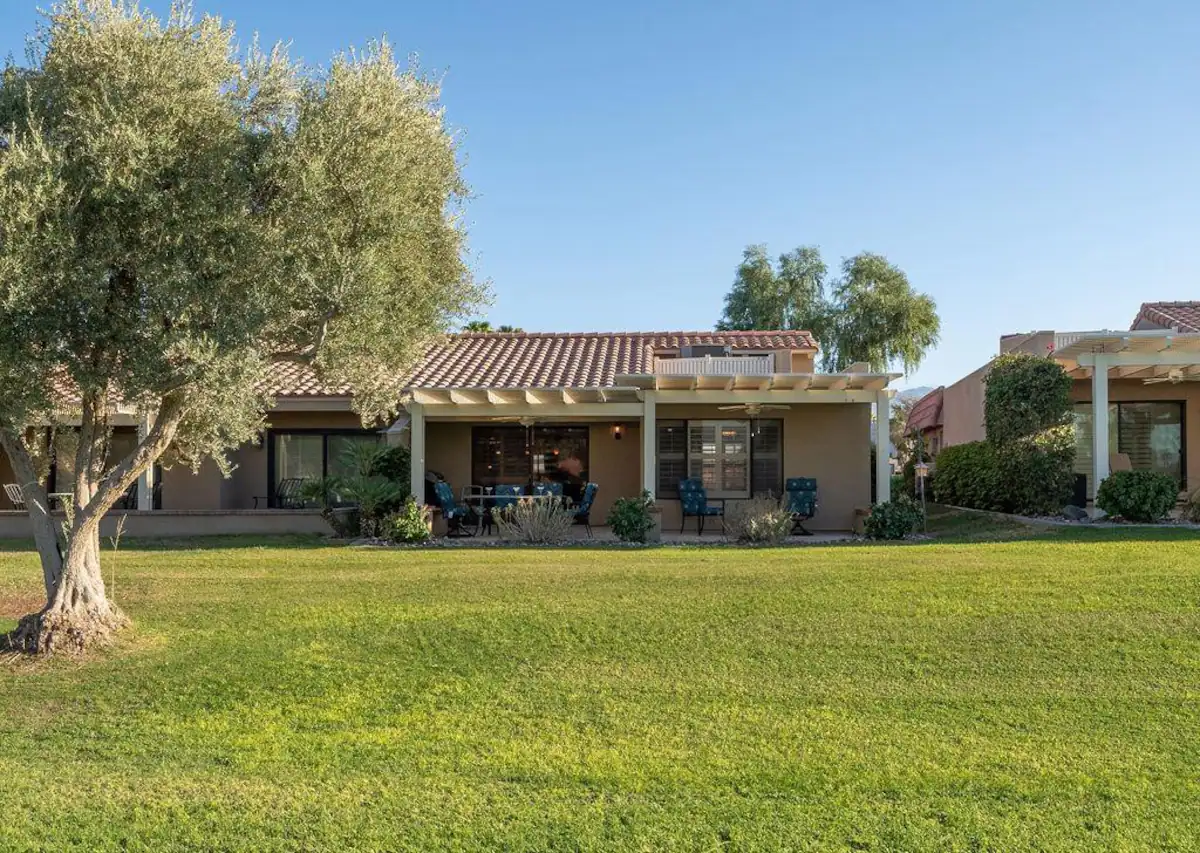outside view of vacation rental in palm desert on a golf course with large trees and outdoor lounge area