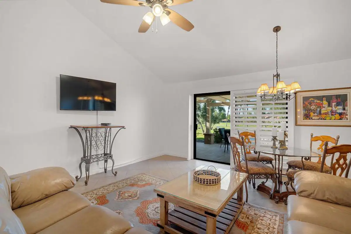 a living room with vaulted ceilings, ceiling fan, and large tan leather couches