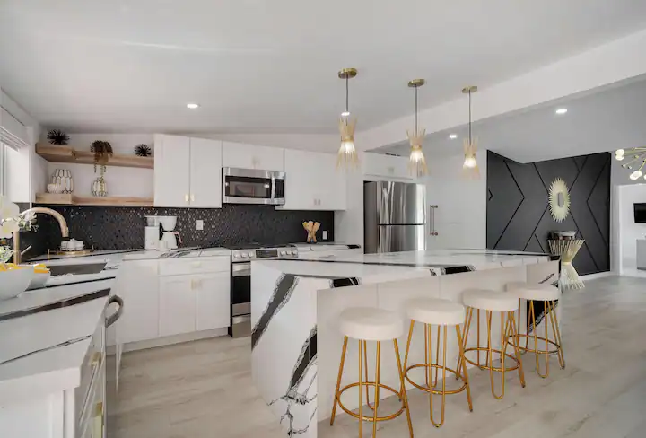 gourmet kitchen in palm desert vacation home with black and white marble countertops, large island, and modern gold and black accents