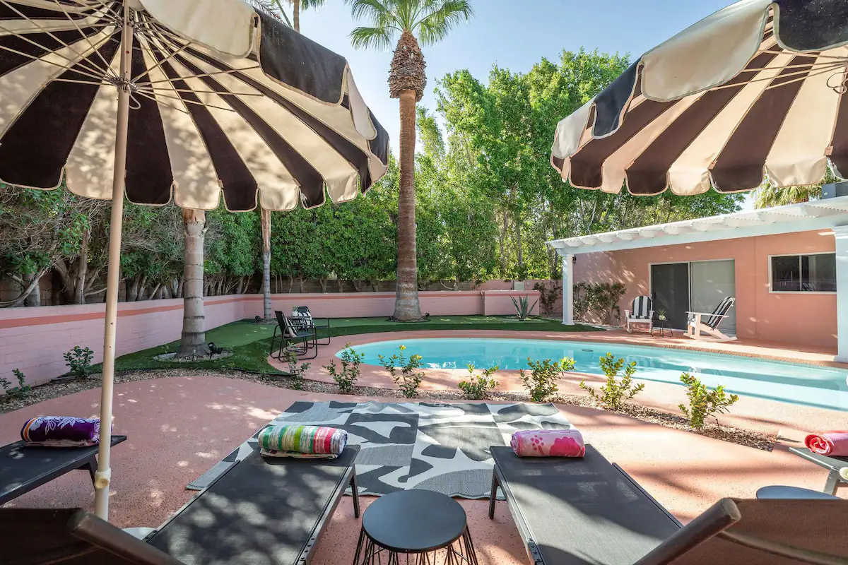 private pool at palm desert vacation rental with lounge chairs, sun umbrellas, and palm trees