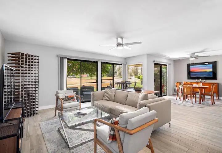 open concept living space in a Coachella valley vacation rental with dining table, leather couches, and large sliding glass doors