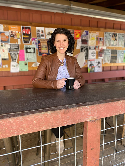 Shelby Wolpa, remote work consultant, smiling with a cup of coffee