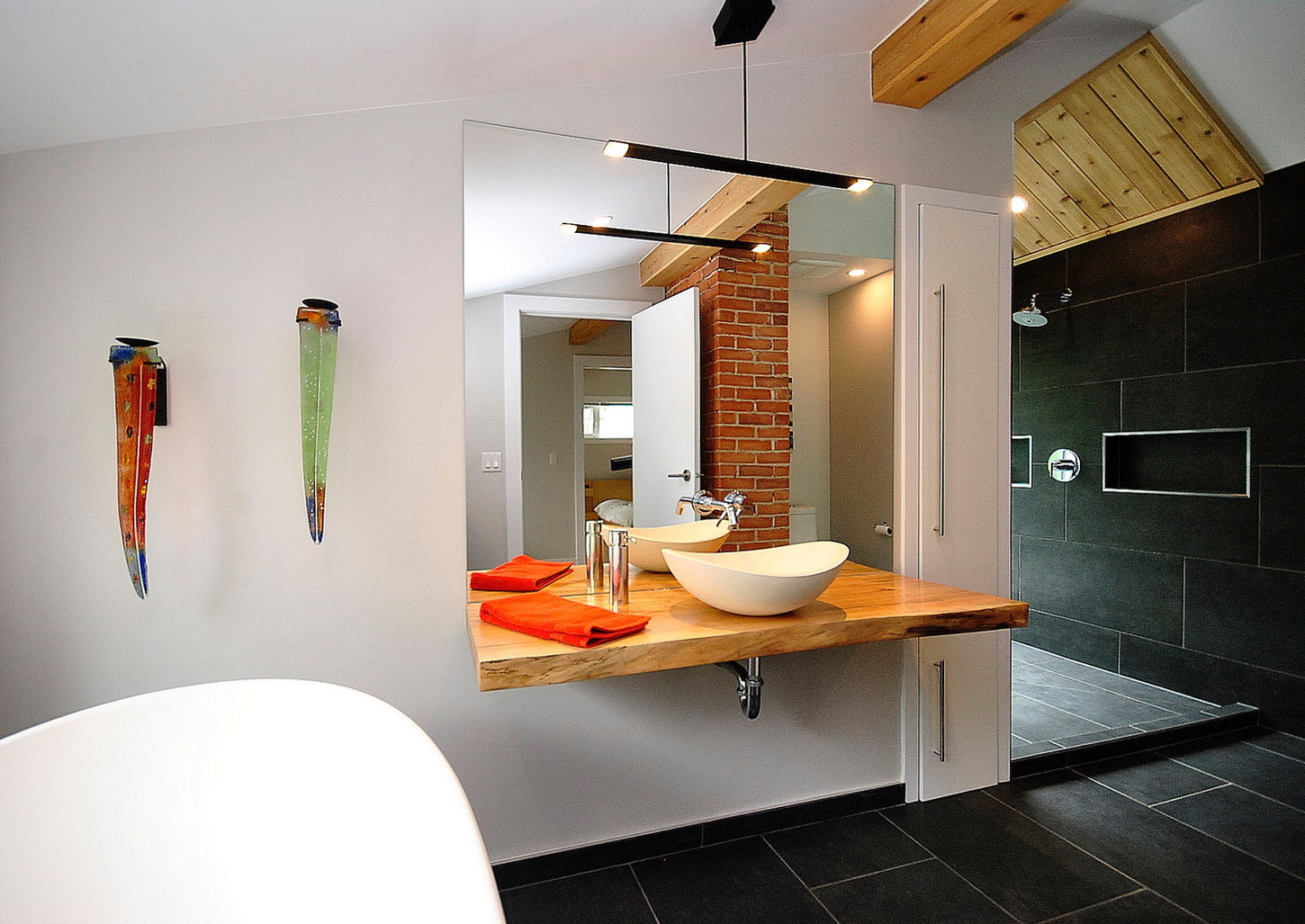 Eclectic bathroom. Floating wood vanity. Vessel sink. Exposed brick. Free standing stone soaker tub.