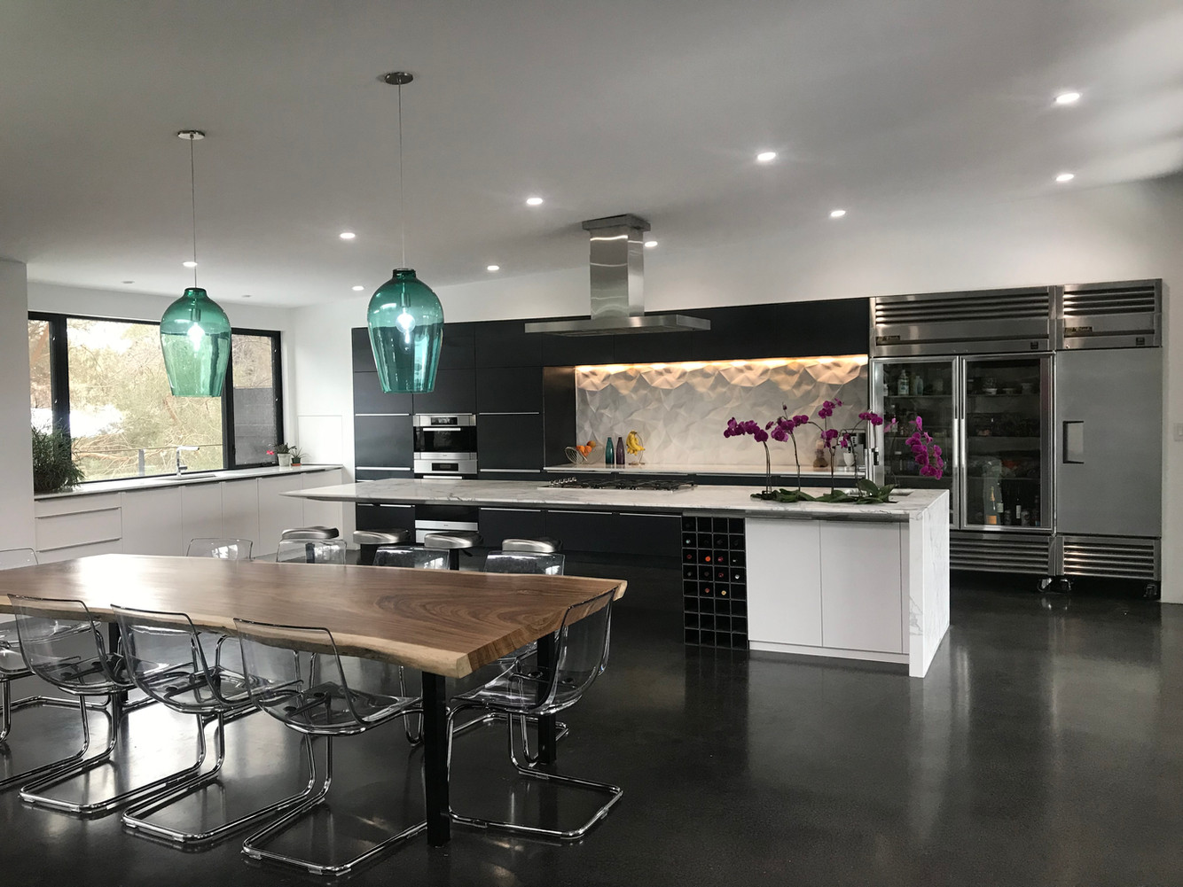 Modern kitchen. White flat cabinets. Raw steel cabinets. 3D tile. Poured charcoal concrete floor. 14' floating island. Statuario marble island countertop.