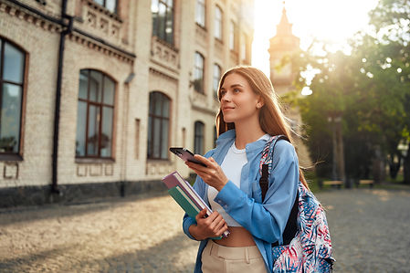 A young female student enjoys modern academic life on campus, using a smartphone while car