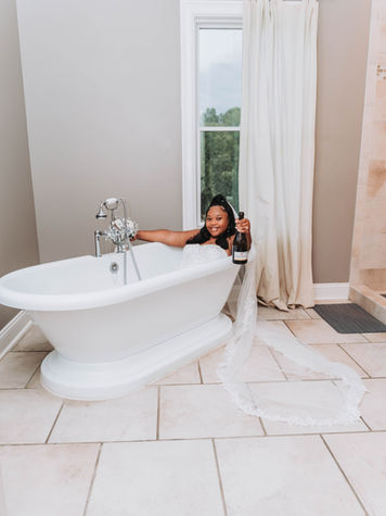 Bride in wedding dress holding champagne in bathtub at The Bradford New Hill NC