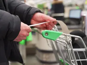 Close up of man holding receipt over grocery cart