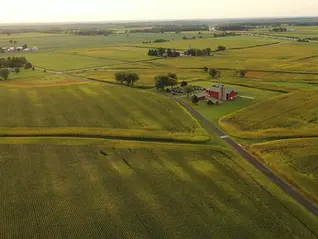 Aerial view of a Midwest farm with a red barn surrounded by cropland