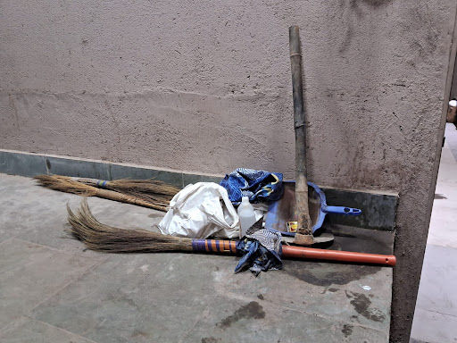 Brooms and other cleaning tools used by crematorium workers lie in a corner.