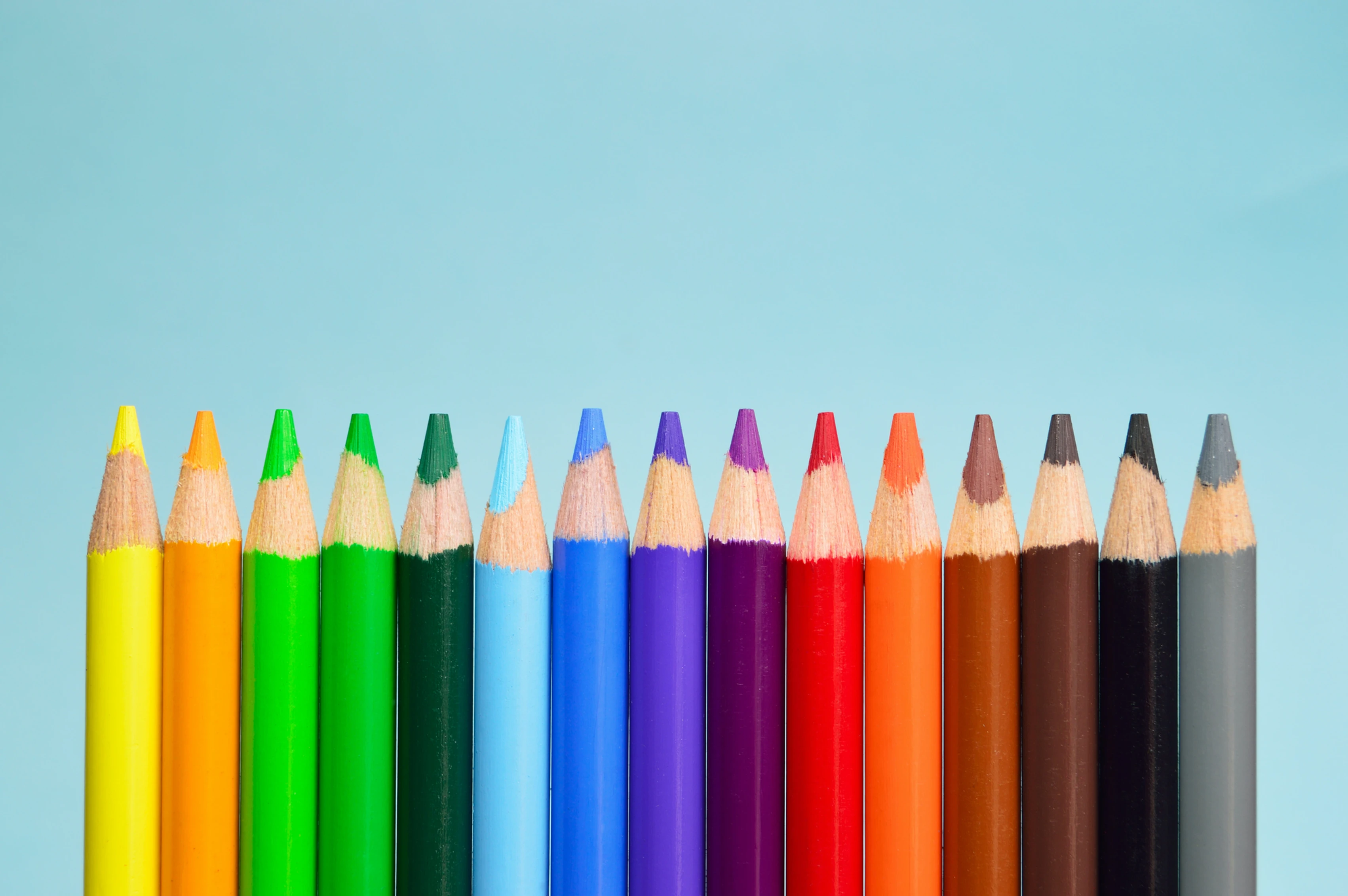 Brightly colored pencils lined straight up against an acqua background.