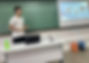 Foto retirado em ambiente escolar onde mostra o Kauan apresentando os membros da iniciativa em uma apresentação de slide.