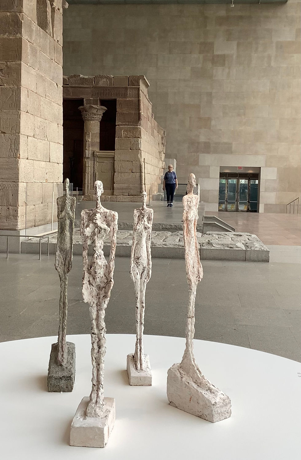 Giacometti’s female sculptures in the foreground with artist Rossella BLUE Mocerino standing in the background at The Met exhibit.