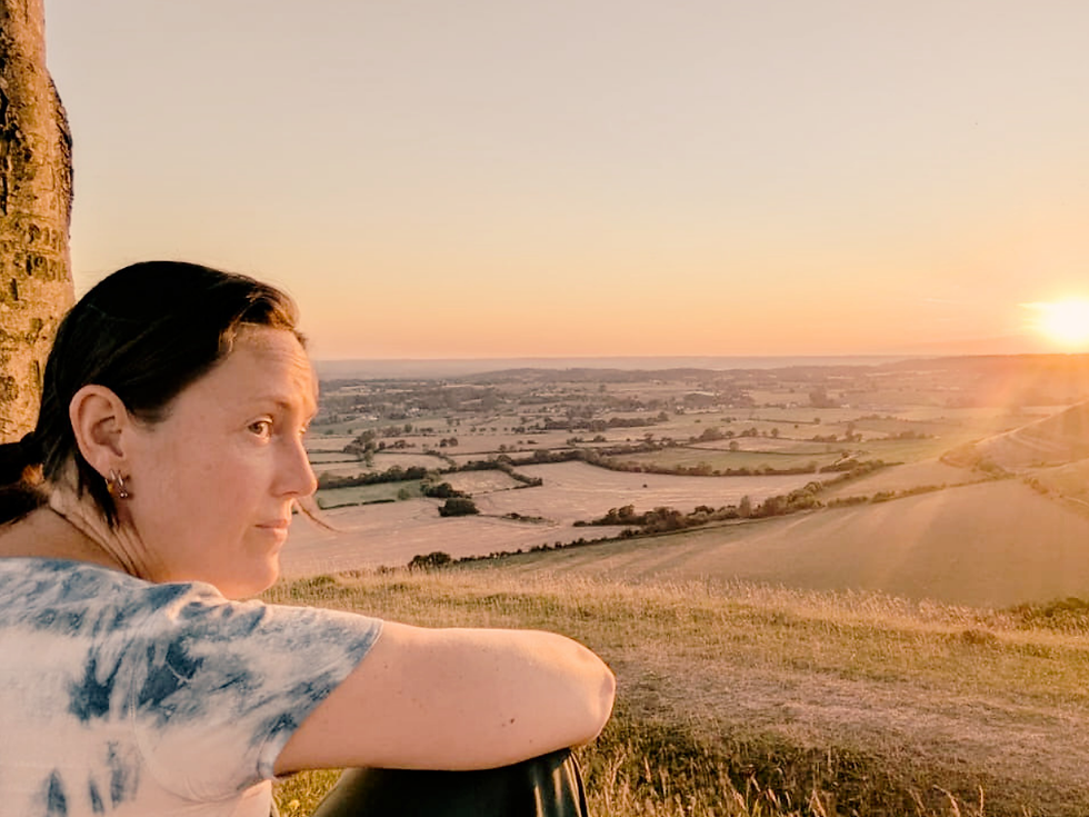 woman sitting at a viewpoint looking into the sunset