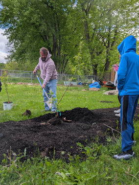 Jim of Grow With Gordon teaches young people to plant a fruit tree at The Refuge Community Garden in Kokomo.