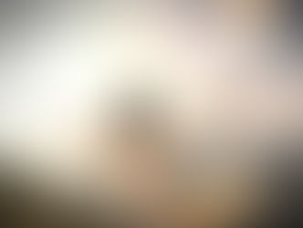 Woman in a sheer white dress stands on sunlit cliffs, arms outstretched toward the sea and distant islands, feeling free