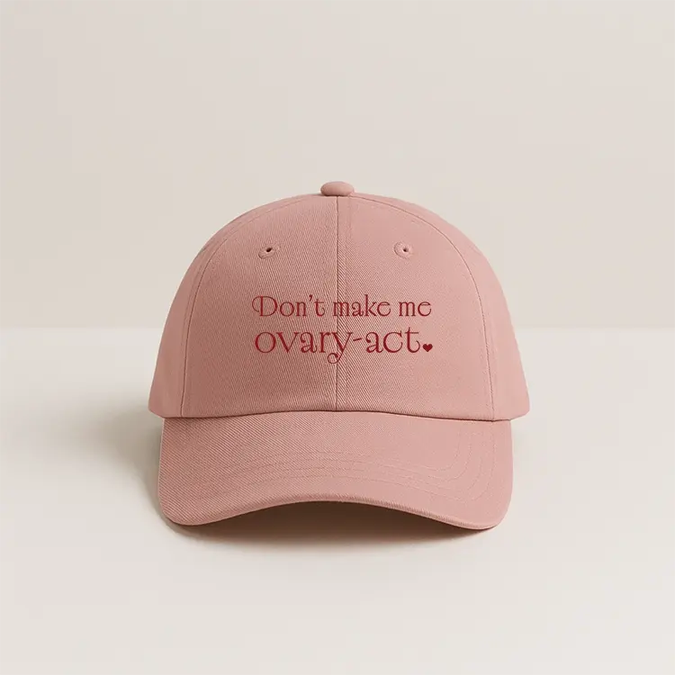 Pink women’s cap with “Don’t Make Me Ovary-Act” embroidered typography design.