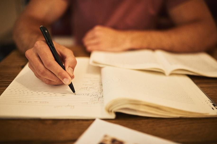 man writing in notebook. blog image for 5 ways to enhance your writing style blog by Purposeful Prose