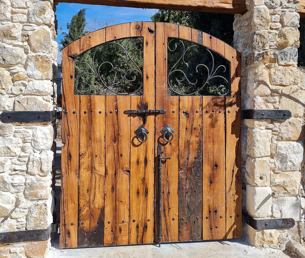 Handcrafted wooden gate with iron details set in rustic stone frame