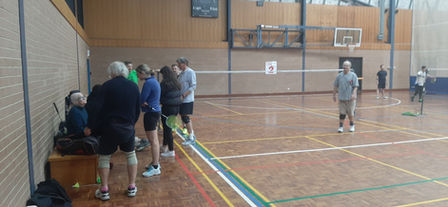 Social gathering on side of badminton court.