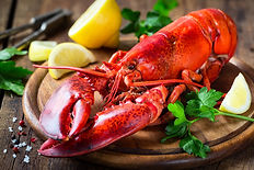 Steamed red lobster on a wooden cutting board with parsley and lemon