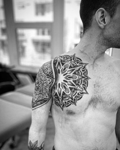 A mandala line art tattoo on the shoulder and chest
